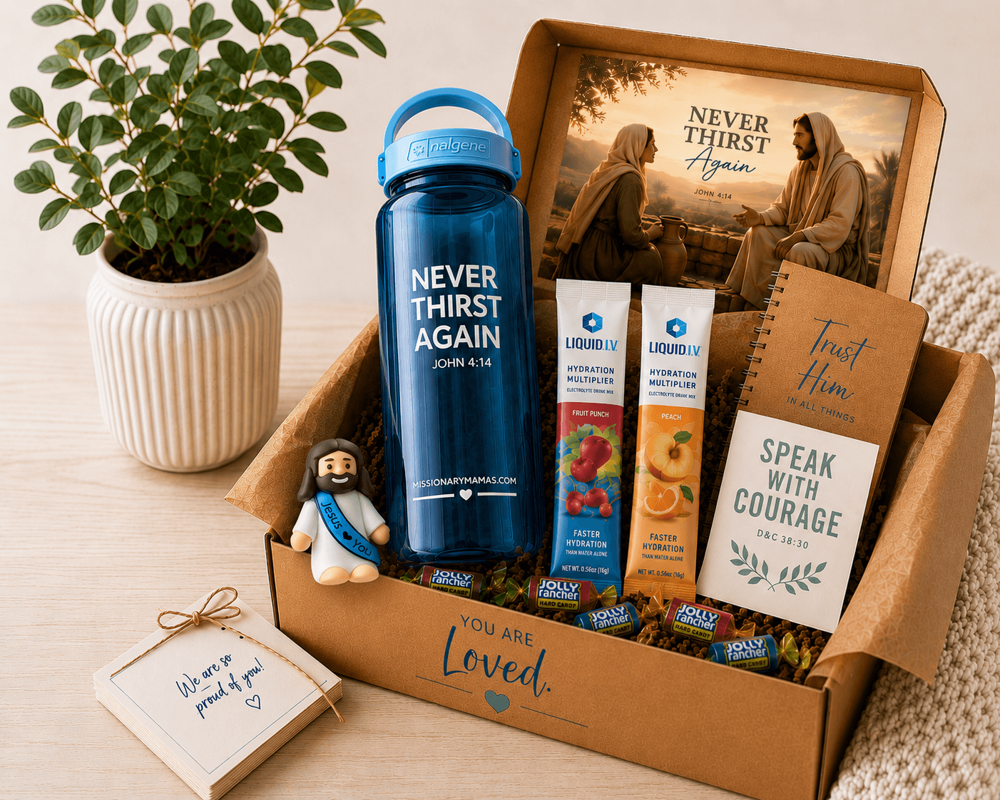 An open Missionary Mamas care package with a scripture water bottle, hydration drink packets, candy, a journal, and encouraging scripture cards